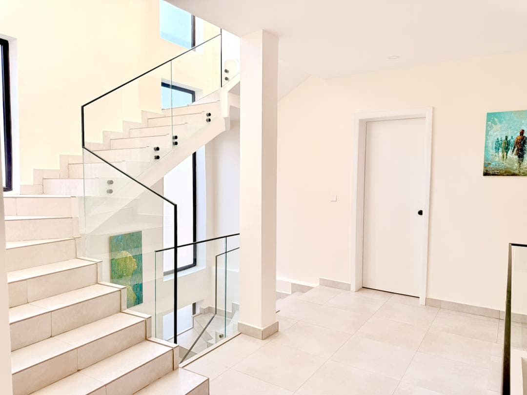 Bright white staircase lobby with glass railing and artwork